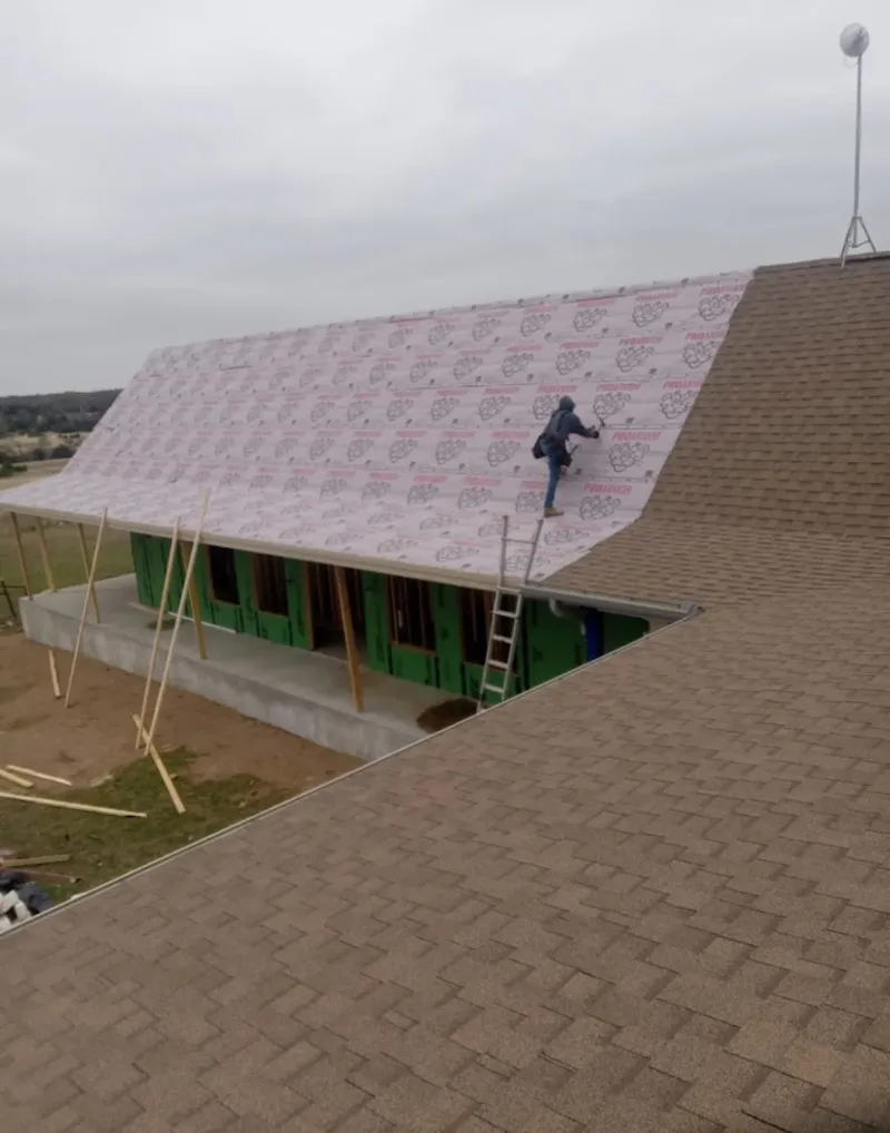 Worker preparing underlayment for a metal roof installation in Arvada